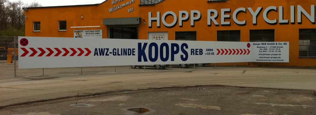 Großes Werbebanner von Koops Recycling auf Absperrung vor Industriehalle in Glinde. Beispiel für Bauschilder und Werbebanner von Folien Fischer Hamburg Bergedorf, Reinbek, Glinde, Schwarzenbek und Lüneburg